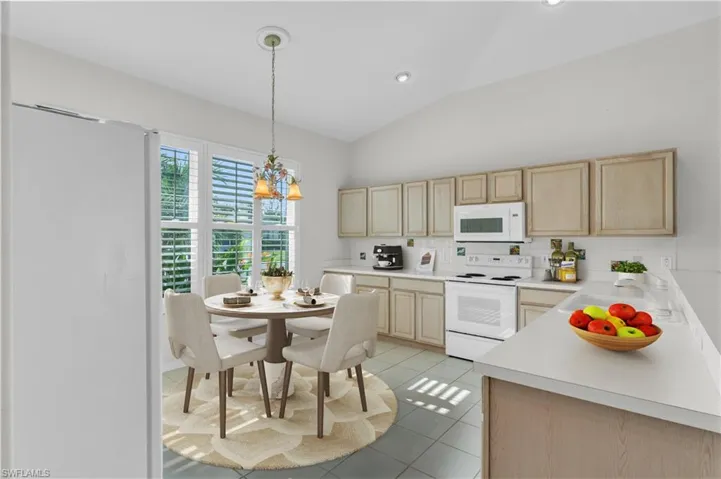 Kitchen featuring sink, white appliances, vaulted ceiling, tasteful backsplash, and light brown cabinets