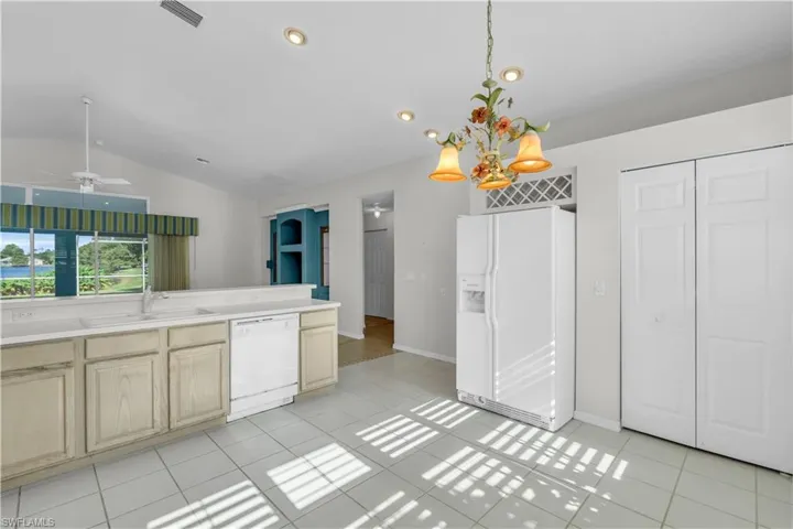 Kitchen featuring ceiling fan, light tile patterned floors, decorative light fixtures, lofted ceiling, and white appliances