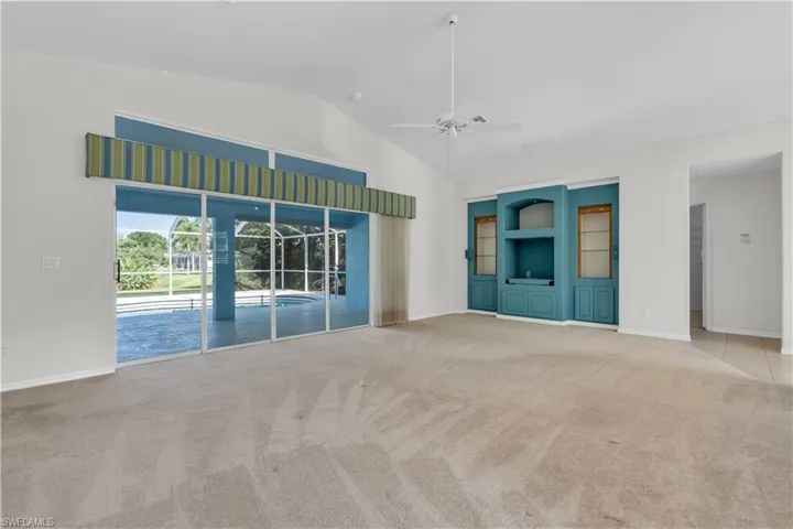 Unfurnished room featuring carpet floors, ceiling fan, and high vaulted ceiling