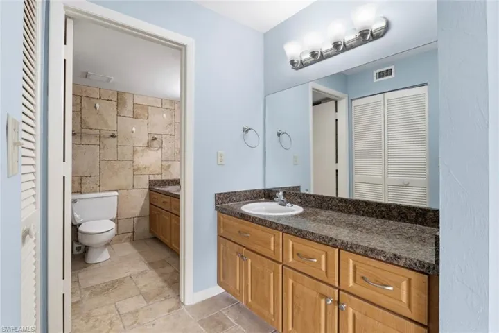 Bathroom featuring a closet, vanity, and stone tile floors