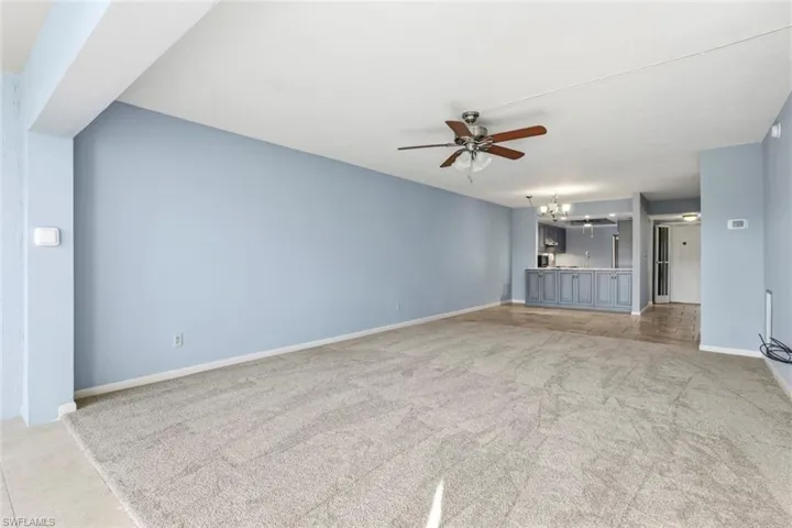 Unfurnished living room with suspended lighting, ceiling fan, and new carpet