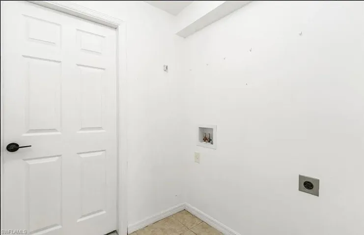Washroom with hookup for a washing machine, electric dryer hookup, and light tile patterned floors