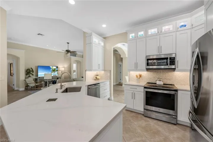 Lighted upper cabinets showcase your special vases. White shaker cabinetry, arched entry ways, updated with style.