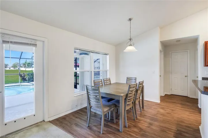 Dining area featuring vaulted ceiling and dark wood-style floors