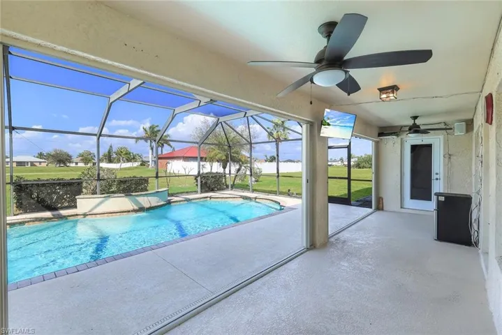 Outdoor pool with a patio area, glass enclosure, a sunroom, and a yard