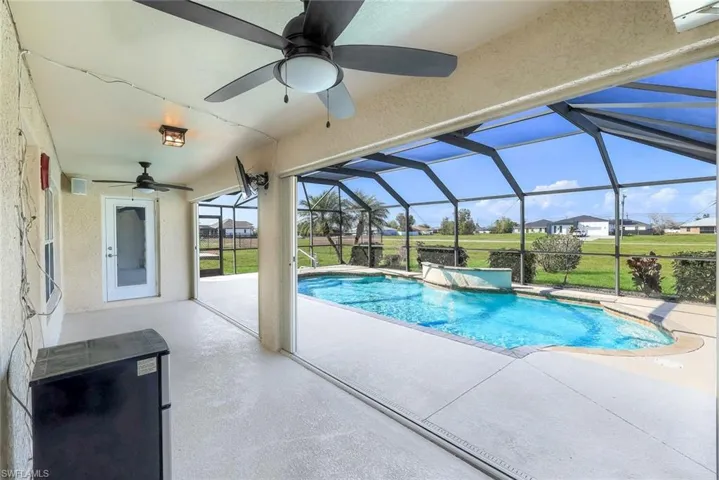 Swimming pool with a sunroom, a patio, glass enclosure, and a residential view