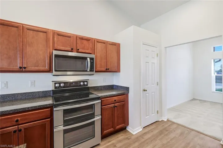 Kitchen with stainless steel appliances, light wood-style floors, wood finish cabinetry, and vaulted ceiling