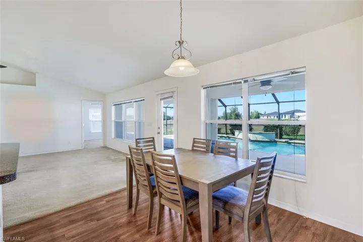 Dining area with vaulted ceiling, wood finished floors, and a sunroom