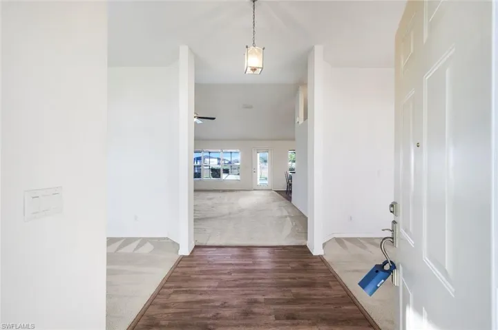 Foyer with light colored carpet, light wood-style flooring, and a ceiling fan