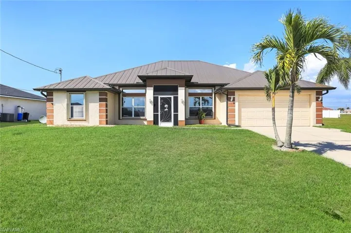 View of front of home with a front lawn, a garage, driveway, and stucco siding