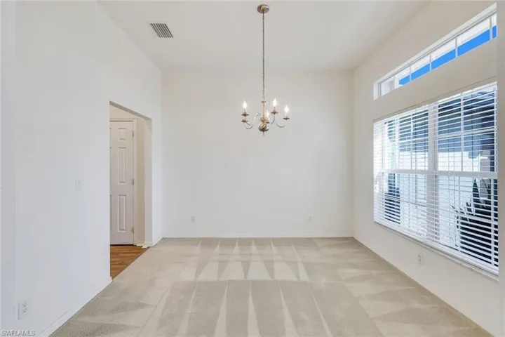 Unfurnished room featuring a chandelier and light colored carpet