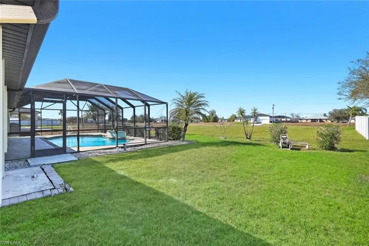 View of green lawn featuring a sunroom, a lanai, an outdoor pool, and a patio area