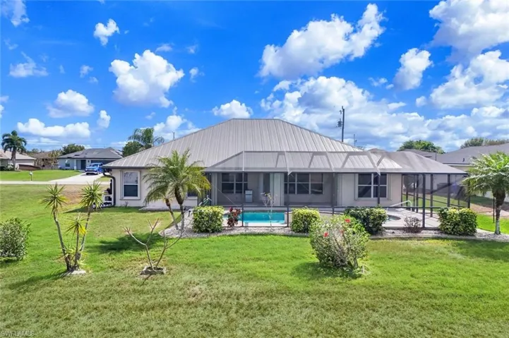 Back of property featuring a sunroom, a yard, an outdoor pool, and a lanai