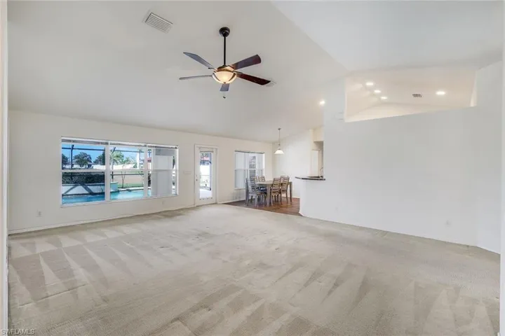 Unfurnished living room featuring a ceiling fan, light carpet, vaulted ceiling, and recessed lighting