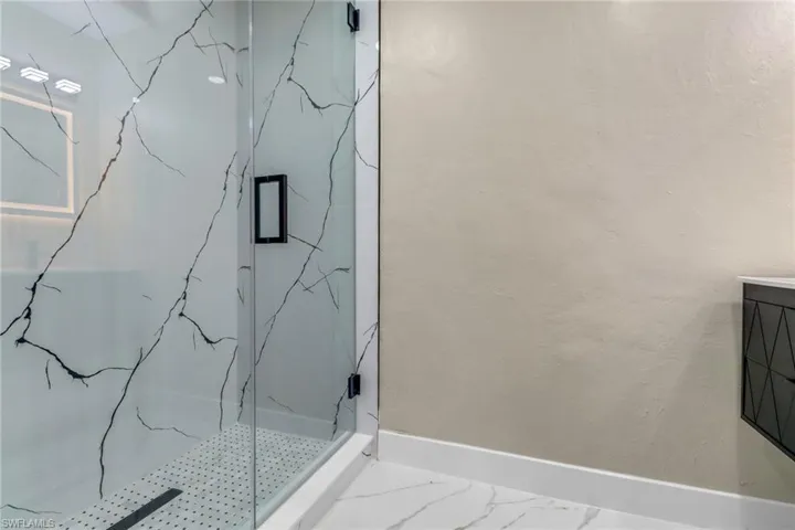 Full bath featuring a marble finish shower and vanity