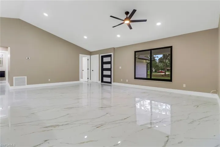 Unfurnished living room featuring vaulted ceiling, light marble finish floors, recessed lighting, and a ceiling fan