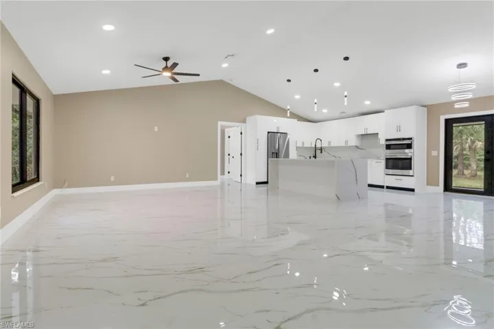 Unfurnished living room featuring light marble finish floors, recessed lighting, high vaulted ceiling, and ceiling fan