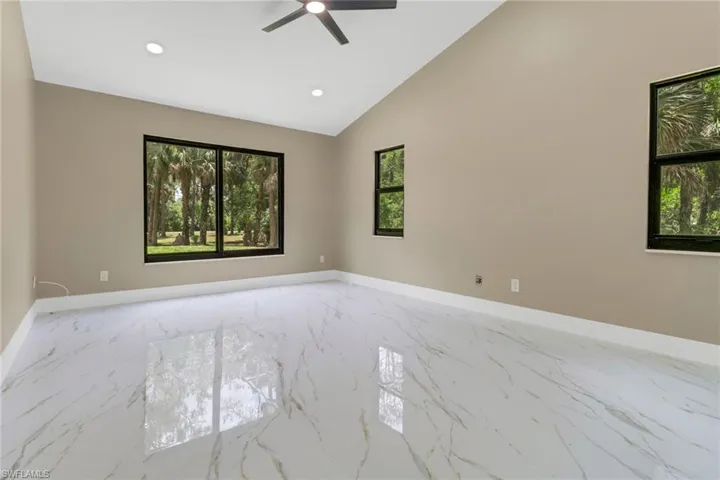 Spare room featuring light marble finish flooring, ceiling fan, plenty of natural light, recessed lighting, and vaulted ceiling
