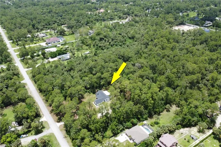 Aerial view of property and surrounding area with a forest