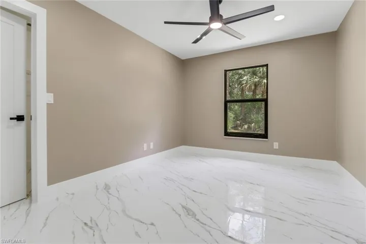 Empty room with marble look tiles, ceiling fan, and recessed lighting
