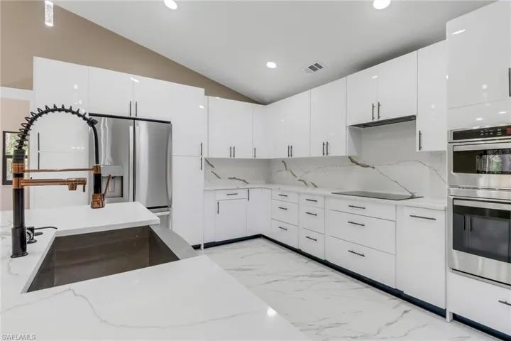 Kitchen featuring stainless steel double oven, light marble finish floors, recessed lighting, white cabinetry, and light stone counters