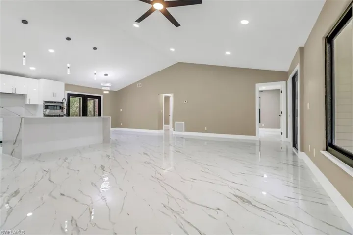 Unfurnished living room with light marble finish floors, ceiling fan, lofted ceiling, and recessed lighting
