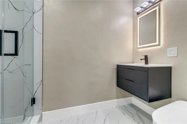 Full bath with vanity, a stall shower, and marble look tile flooring