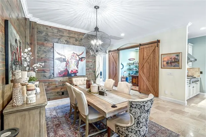 Dining space with a barn door, crown molding, a chandelier, stone tile floors, and recessed lighting