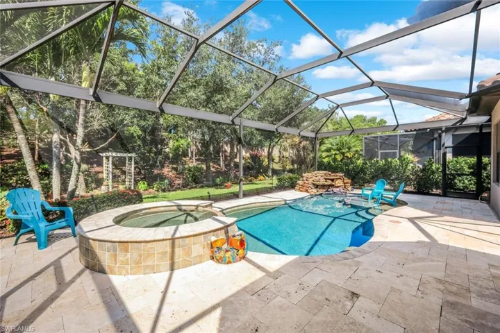 View of pool featuring a patio area, glass enclosure, and a pool with connected hot tub