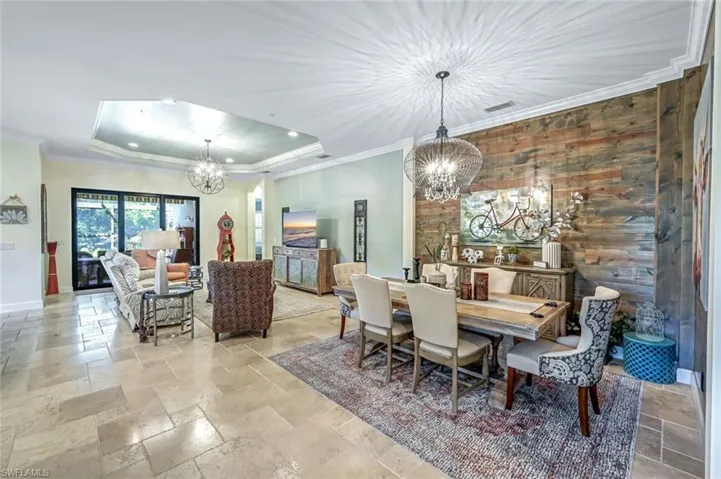 Dining area featuring a chandelier, stone tile flooring, a tray ceiling, recessed lighting, and crown molding