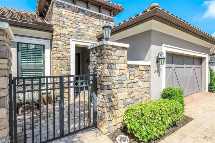 Doorway to property with stone siding, stucco siding, a tiled roof, driveway, and a garage