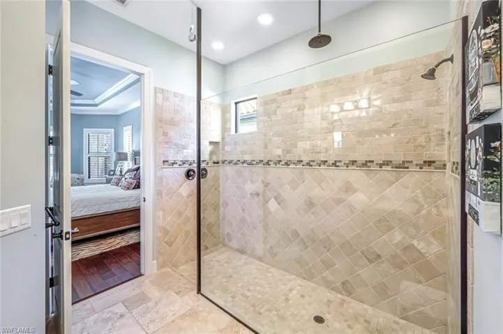 Bathroom featuring connected bathroom, a tile shower, stone finish floors, recessed lighting, and ornamental molding