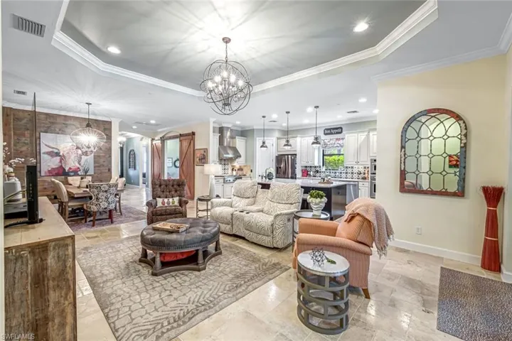 Living area featuring a chandelier, a tray ceiling, crown molding, and recessed lighting