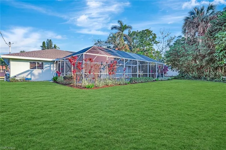 Back of property featuring a lanai and a lawn