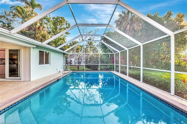 View of pool with screen enclosure and a patio