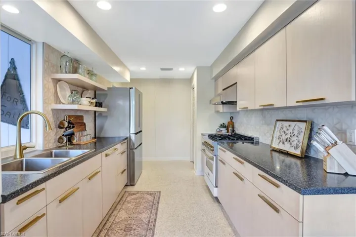 Kitchen with decorative backsplash, stainless steel fridge, high end white range oven, exhaust hood, and sink