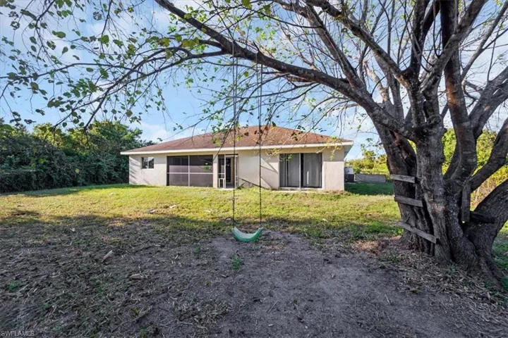 Back of house featuring stucco siding and a lawn