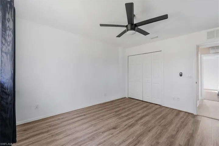 Unfurnished bedroom featuring wood finished floors, ceiling fan, and a closet