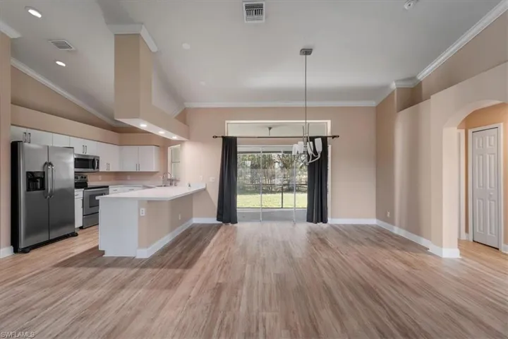 Kitchen featuring stainless steel appliances, light countertops, crown molding, white cabinets, and arched walkways