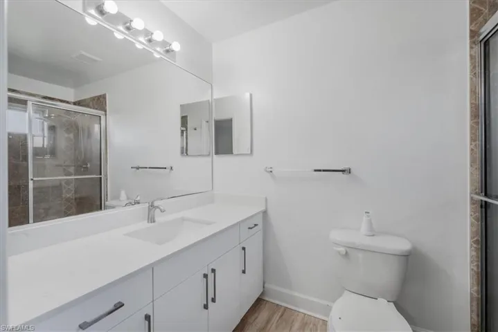Full bath featuring a stall shower, vanity, and light wood-style flooring