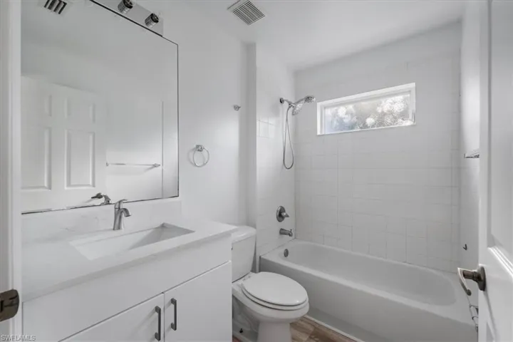 Bathroom featuring  shower combination, vanity, and wood finished floors