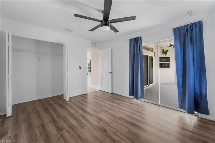 Unfurnished bedroom with wood finished floors, access to exterior, ceiling fan, and a closet