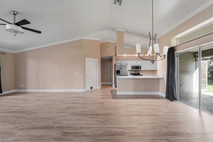 Kitchen with open floor plan, crown molding, a chandelier, light countertops, and light wood-style flooring