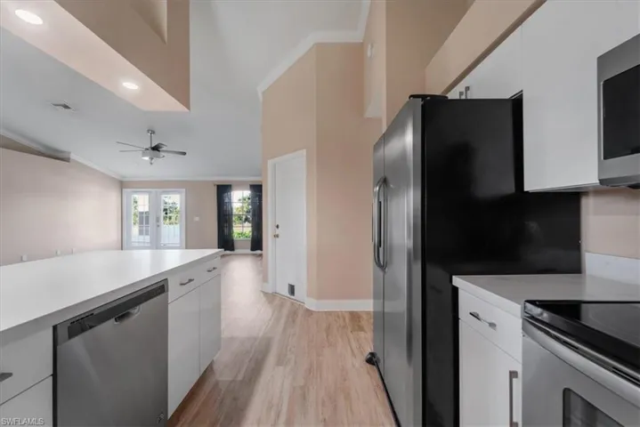 Kitchen featuring crown molding, white cabinets, stainless steel appliances, light countertops, and recessed lighting