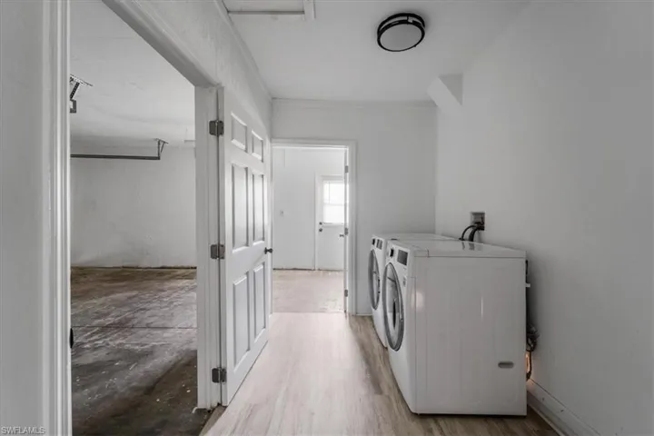Washroom with washing machine and clothes dryer and light wood-type flooring