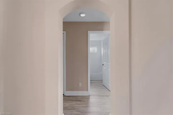Hall featuring arched walkways and light wood-style floors