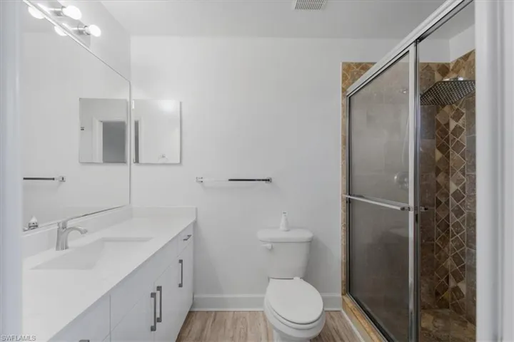 Full bathroom with vanity, a shower stall, and light wood-type flooring