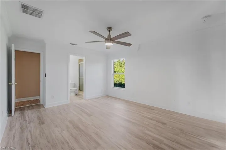 Unfurnished bedroom with light wood finished floors, a ceiling fan, crown molding, and ensuite bathroom