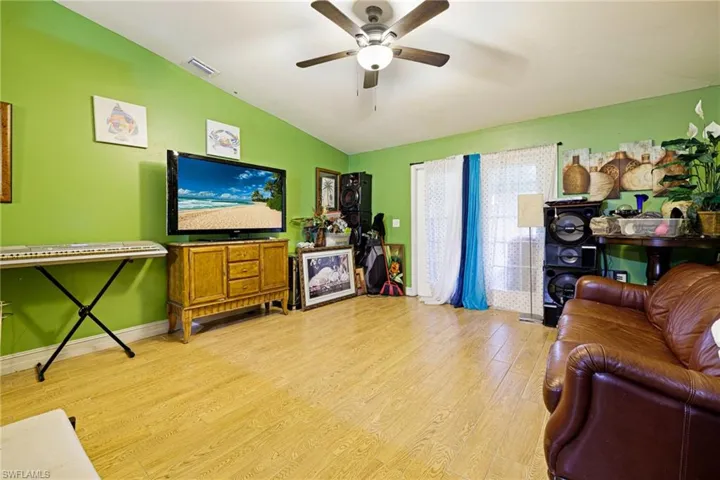 Living room featuring lofted ceiling, light wood finished floors, and ceiling fan