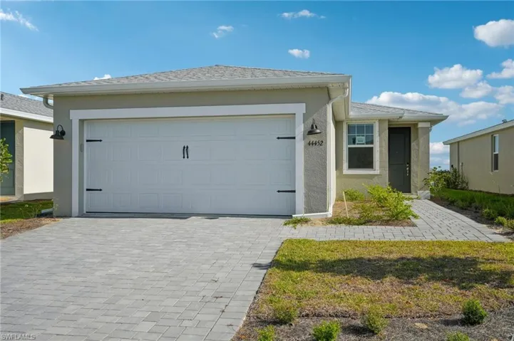 Ranch-style house featuring roof with shingles, stucco siding, decorative driveway, and an attached garage